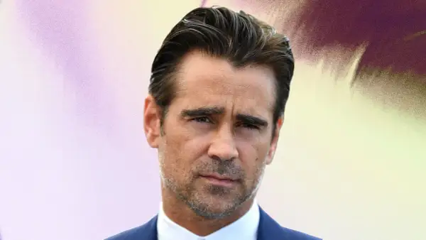 Colin Farrell arbore une coupe de cheveux homme mi long en arrière, un regard intense et un costume bleu.